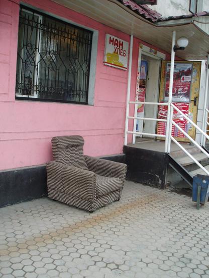 photo of a soft armchair standing out in the street in front of a bread shop in almaty
