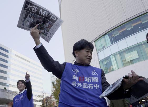 A staff from Asahi Newspaper holds up an extra edition about Los Angeles Dodgers two-way player Shohei Ohtani's MVP award ...