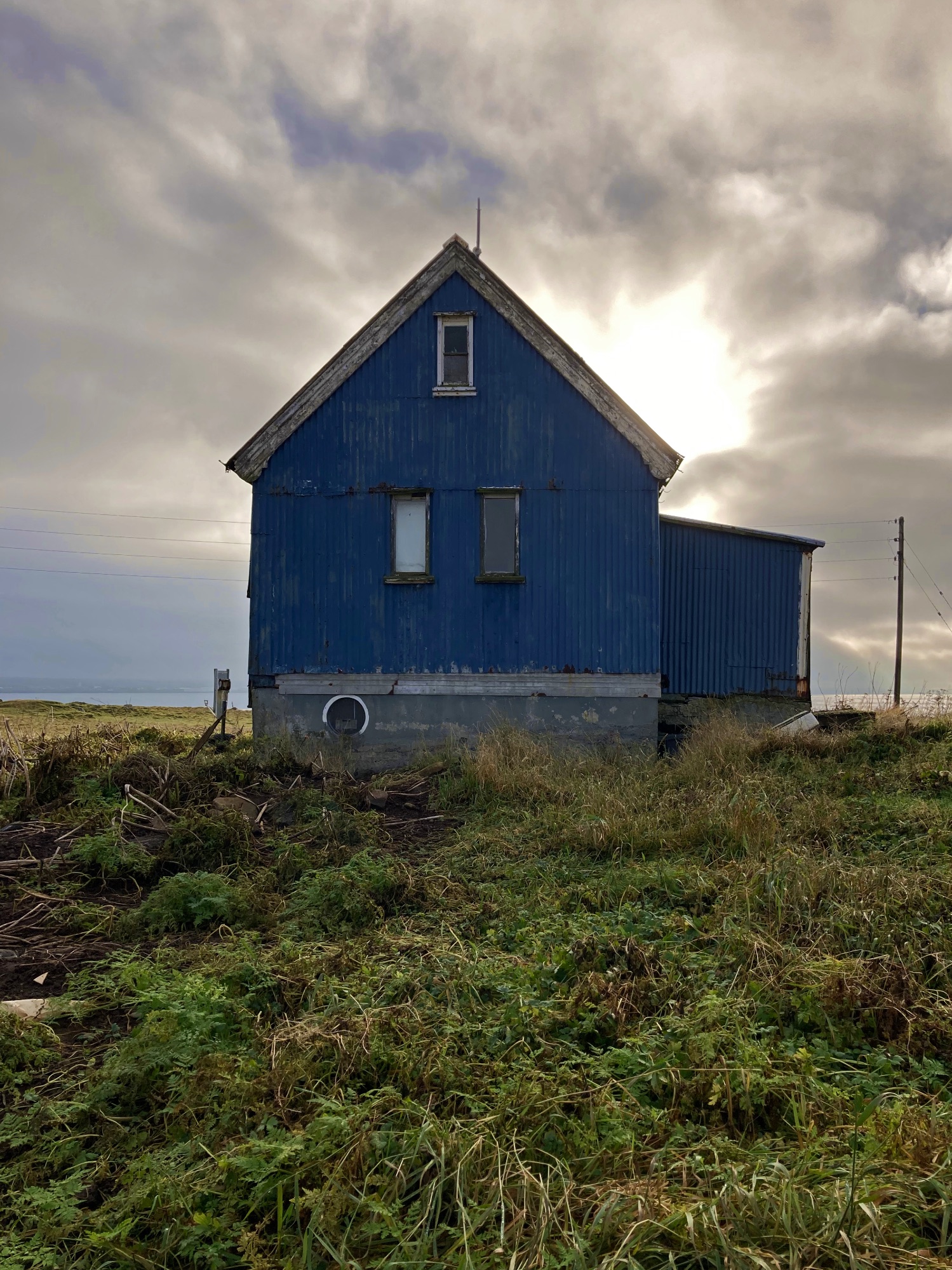 An abandoned old house with the sea and the sun in the background.