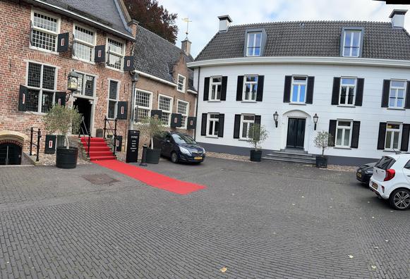 Left the castle with typical green, red and white window shutters. On the right a white house with green window shutters.