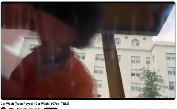 Man with afro and a building behind him