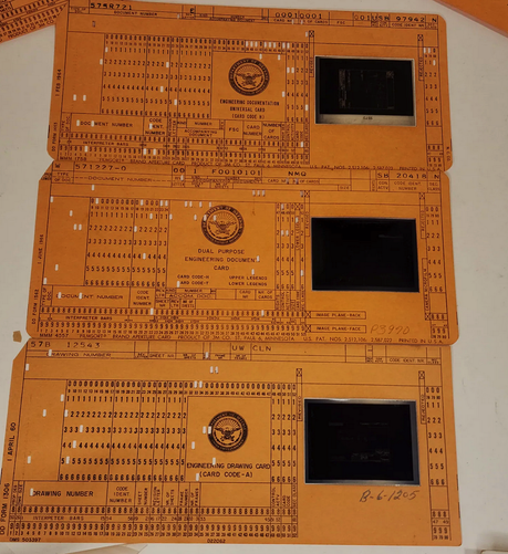 Computer punch cards with a hole in them, in the window is a microfiche