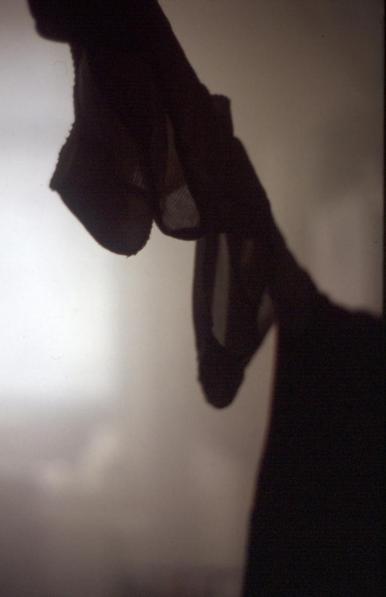 Im Vordergrund ist eine Wäschleine mit verschiedenen Wäschestücken. Alle sind im Gegenlicht nur als teilweise durchscheinende Shilouetten zu sehen. Das ganze Zimmer ist mit Wasserdampf gefüllt. Hinten links ist ein helles Fenster zu erkennen.