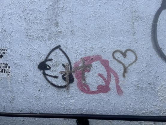 One unhappy graffiti head, one vaguely happy graffiti head, both with a cross slapped over them