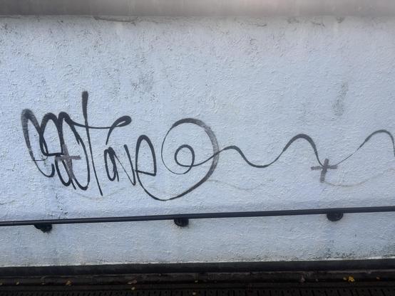 A graffiti tag on a wall with two tiny crosses daubed over two parts of it, mayhap covering 3% of the tag