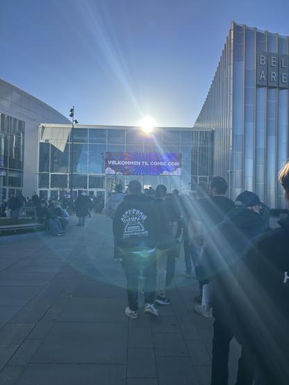 The entrance to Bella Center in Copenhagen, emblazoned with a huge "welcome to Comic Con" billboard and backlit by a bright, low autumn sun in a clear blue sky