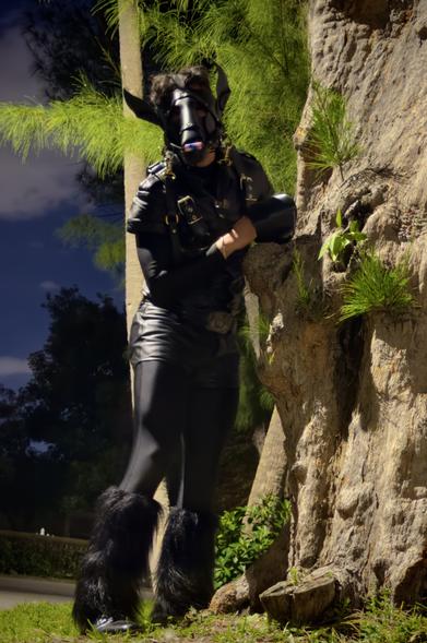 Person in black pony costume standing by a textured tree, playfully leaning out as if playing peekaboo on a suburban lawn at night