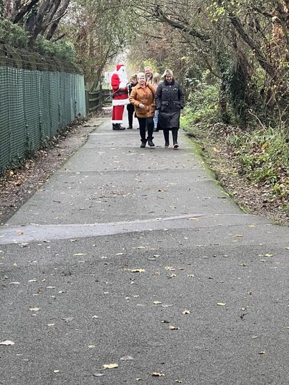 Group of walkers including a father christmas on a tree covered walking path