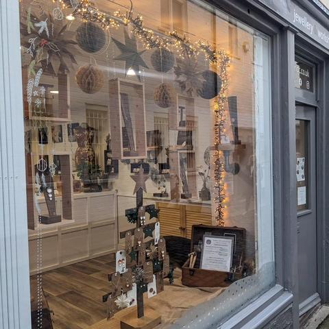 Closer view of the shop window, showing the hanging wooden boxes, paper decorations and fairy lights