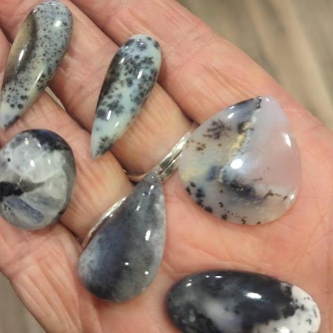 Selection of dendritic opal stones held on an outstretched hand