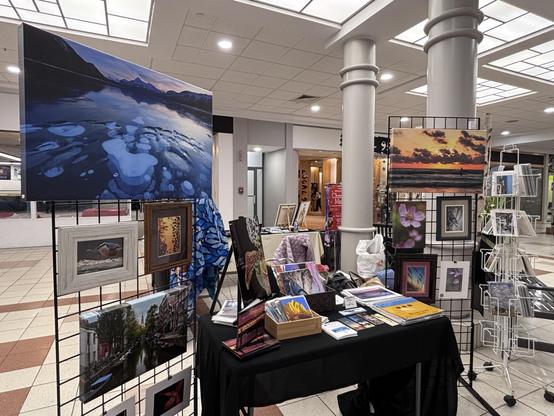 Display table for Photos By Gina. Two grid walls boast framed and canvas prints; a table has smaller items like calendars and bookmarks.