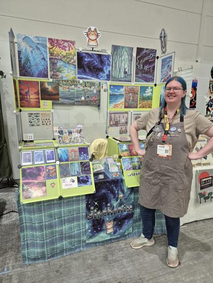 Dinchen standing in front of her artist alley table at Polaris