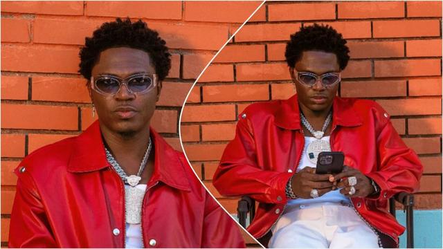 Spyro sits against an orange brick wall wearing a red leather jacket, white inner shirt, layered silver chains and rings, and clear-framed sunglasses; in one image he looks at the camera, and in the other he looks down at his phone.