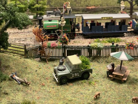 A model railway scene with a steam engine at the back, a zookeeper’s Land Rover in front, goats munching on grass etc.