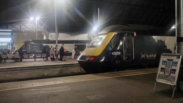 Looking across several platforms and tracks at night in Glasgow's Queen Street Station, a pair of intercity trains awaiting their next passengers