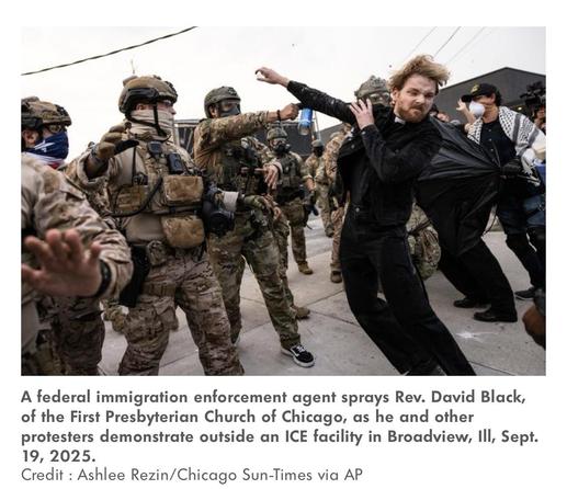 Rev Black, with his arm toward the armed fed agents at a protest, as he is pepper sprayed.