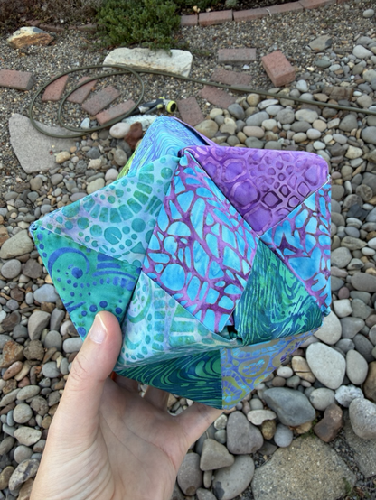 Turquoise, purple and green fabrics folded into an OctaHedron this view shows how the modular fabric origami is fitting together.