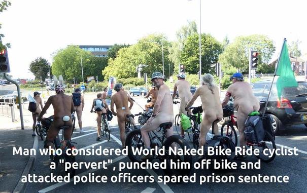 Eine Gruppe von Menschen steht auf Fahrrädern in einer Straße, wobei die meisten keine Kleidung am Oberkörper tragen. Sie stehen in einer Reihe, wobei die Fahrräder in Fahrtrichtung zeigen. Im Hintergrund sind Autos, Bäume und Verkehrsschilder zu sehen. Der Boden der Straße ist asphaltiert, und der Himmel ist bewölkt. Der Text im Bild lautet: "Man who considered World Naked Bike Ride cyclist a 'pervert,' punched him off bike and attacked police officers spared prison sentence".