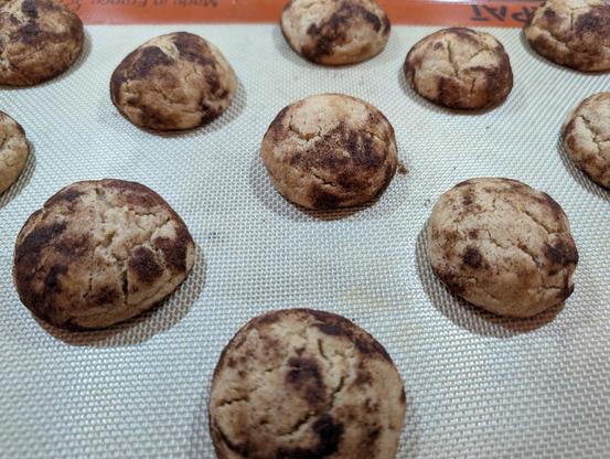 A baking sheet with a dozen baked snickerdoodle cookies