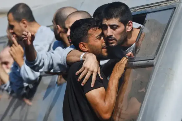 Recently released Palestinian prisoner hugs someone through the open window of a bus.