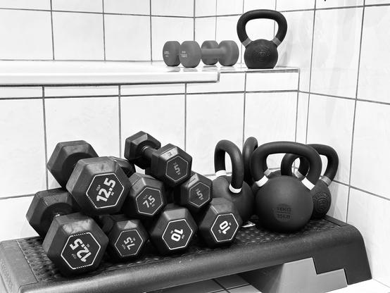 Kurzhanteln und Kettlebells vor einer Badewanne