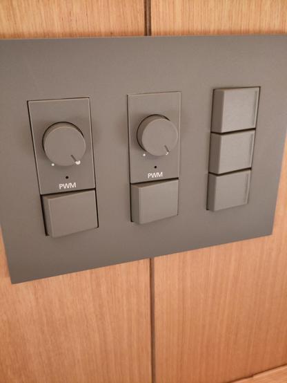 A brown hotel lighting switch panel with rotary brightness controls labelled PWM. Several unmarked flip switches are also present.
