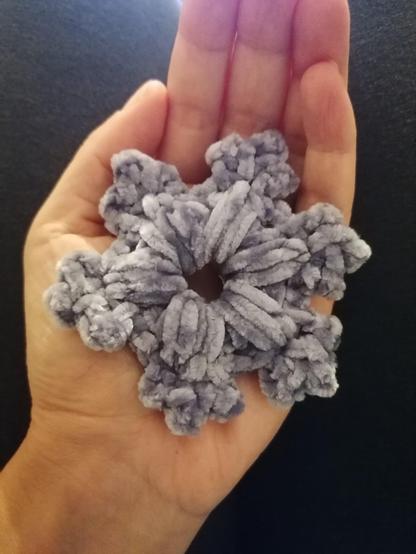 Un fiocco di neve sofffffice sofffffice, lavorato all'uncinetto e pronto per diventare una decorazione dell'albero.