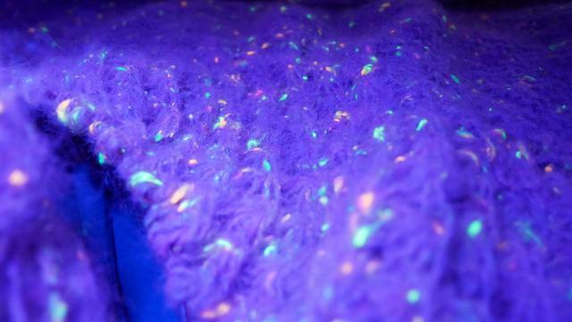 closeup of the yarn showing the neon bits shining under blue uv light