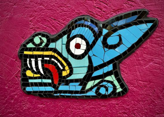 Urban mural detail of a blue coyote head made from reclaimed ceramic tiles on a purple wall