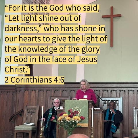 A woman stands at a church pulpit reading aloud during a service. She is framed by two seated clergy members in robes, one on each side, in front of a wooden chancel. A bouquet of yellow and red flowers decorates the front of the pulpit, and a tall wooden cross hangs on the light green wall behind them. A large block of highlighted text overlays the top half of the image, displaying the Bible verse 2 Corinthians 4:6 about God shining light out of darkness.
