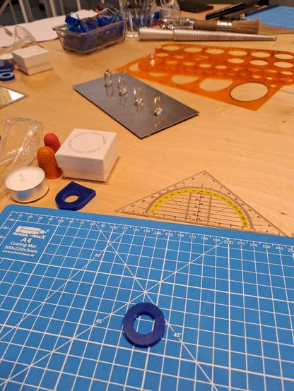 A desk showing with a cutting mat, a blue wax blank and various tools.