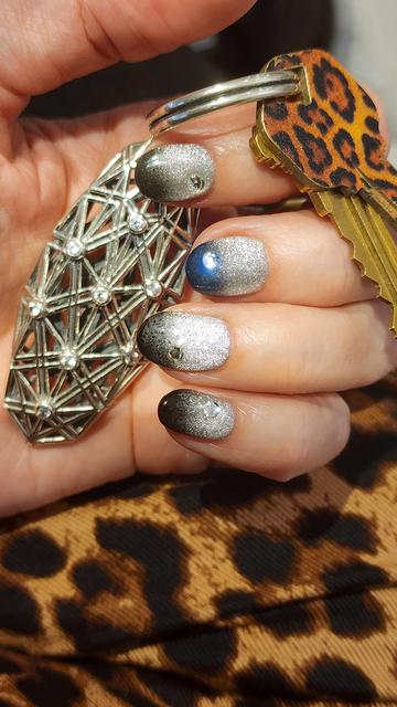 A manicured hand holds a sterling silver keychain peppered with bezel set white sapphires. The fingernails, painted metallic silver and black with white stone embellishments, match the keychains aesthetic.
~
Een verzorgde hand houdt een sleutelhanger van sterlingzilver vast, bezaaid met wit saffier in kastzetting. De vingernagels, beschilderd in metallic zilver en zwart met witte steendecoraties, passen bij de esthetiek van de sleutelhanger.
~
Une main soignée tient un porte-clés en argent sterling parsemé de saphirs blancs sertis en bezel. Les ongles, peints en argent métallique et noir avec des ornements en pierres blanches, s’accordent avec l’esthétique du porte-clés.