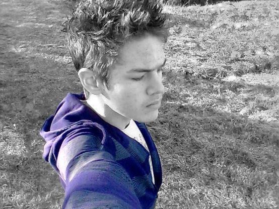 A black and white (and purple of my hoodie) photo of my 17-year-old self taken at arms-length, with me looking in another direction.