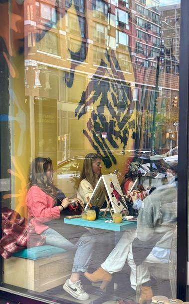 West side Manhattan Paint and Pour, view from the sidewalk. People are painting a dinosaur.