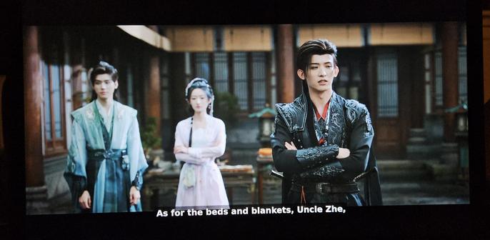 Su Mu Yu and the Miracle doctor in the background watching as Chang He says "As for the beds and blankets, uncle Zhe"