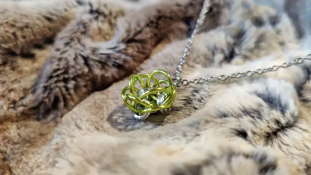 Pendentif en maille qui évoque une petite fleur verte.