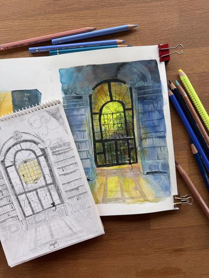 A workspace featuring a colored pencil and watercolour drawing in an open sketchbook and a smaller version of the same scene in just pencil of a large arched window with a view of a library interior.