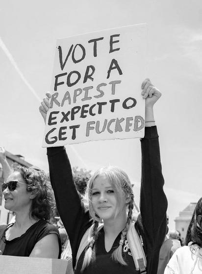 Bildbeschreibung (Deutsch):
Eine junge Frau mit Zöpfen hält auf einer Protestkundgebung ein handgemaltes Schild hoch, auf dem in großen, teils betonten Buchstaben steht:
„Vote for a rapist - expect to get fucked" Sie steht inmitten einer Menge - friedlich, aber entschlossen. Der Ausdruck auf ihrem Gesicht zeigt Klarheit und stille Stärke. Im Hintergrund erkennt man weitere Demonstrierende, sommerliches Tageslicht und einen offenen Himmel.
Das Bild symbolisiert den Aufschrei gegen systemi-sche Dunkelheit, die sich im politischen Gewand tarnt - und die kollektive Resonanz eines neuen Bewusstseins, das beginnt, die Masken der Macht zu durchschauen.
Interpretation im Kontext der Bewusstseinsstufen:
Nur wer auf der untersten Bewusstseinsstufe steht, verwechselt Charisma mit Charakter - und sieht im Dämon das Versprechen von Ordnung. Doch wer tiefer schwingt, erkennt: Das Böse trägt oft das Lächeln des Verführers.🖖