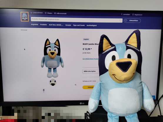 Ein Bluey Plüschtier vor einem Monitor auf dem ALDI Süd Homepage mit der Artikelseite des Plüschtiers angezeigt wird.