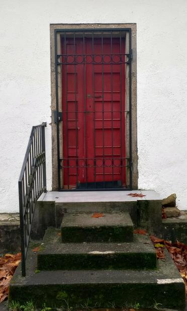 A red door with black metal bars is set in a white wall. Surrounded by a stone frame, the door is accessed by three stone steps with fallen leaves.
#portas #doors #portasvermellas #reddoors #laureanoaraujo #santiagodecompostela #galiza
Santiago de Compostela, 17 de novembro de 2025