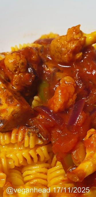 A bowl of  Radiatori pasta w/ herb & lemon infused tofu in a cauliflower & tomato sauce.