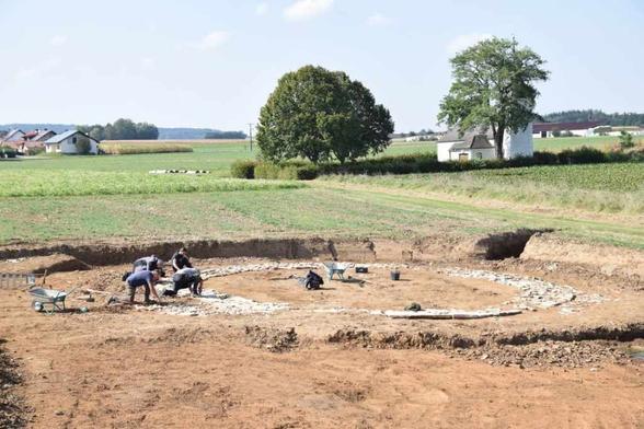 Un gruppo di archeologi sta lavorando su un cerchio di pietre di circa 12 metri di diametro, con una struttura quadrata a sud, in un'area rurale di Wolkertshofen, Baviera.