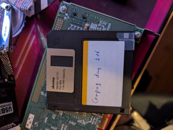 A picture of a 3.5 inch floppy laying atop a PCI-X card of some kind.
The label reads "Compaq Diag 286" it is hand-written.