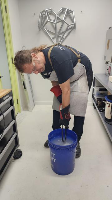 Duane quenches a flask in a 5 gallon bucket of water at Xover0 Jewelry Studio. 
~
Duane dooft een kolf in een vijf-gallon emmer water in de Xover0 Jewelry Studio.
~
Duane trempe un flacon dans un seau de cinq gallons d’eau au studio de joaillerie Xover0.