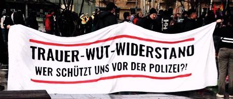 Demonstration, die Menschen tragen ein Plakat auf diesem steht in Großbuchstaben
"Trauer-Wut-Widerstand"

Unterzeile auf dem Plakat: "Wer schützt uns vor der Polizei?!"