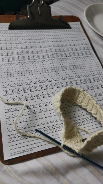 the drawing in question, on my clipboard. just the linework so far, mostly a braid and "stages of rice growth" motif typical of precolonial South Asian/Philippine tattooing (batak). also a pencil sketch of the hand lettered words: "become ungovernable" between what will be a double row of snake teeth, but the "ble" is not drawn yet. also the cuff of what will eventually become a very small offwhite legwarmer is laying atop the drawing, the small blue crochet hook sticking out of it holding my place for when im ready to work on it again