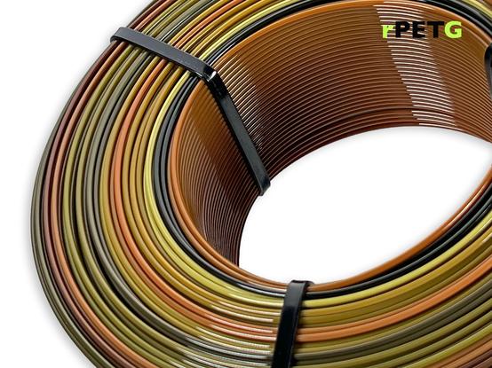 A close up of a refill rPETG spool on white background. We can see the color changing from brown to black to violet.
