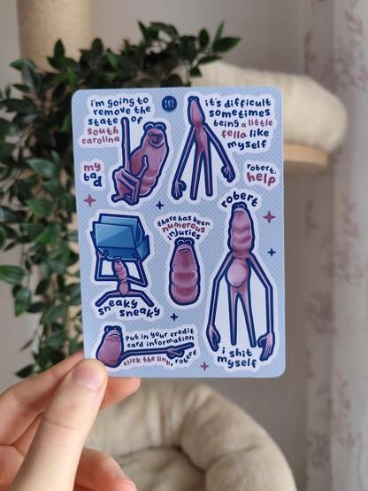 hand holding up a sticker sheet of marcus with his quotes