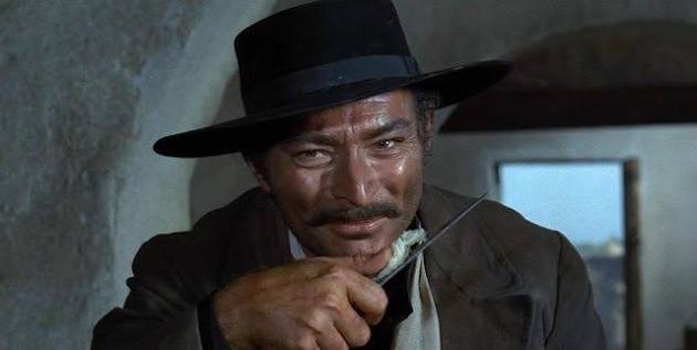Lee van Cleef, grinning and fingering a knife as "Angel Eyes" in Sergio Leone's film "The Good, The Bad, and The Ugly"