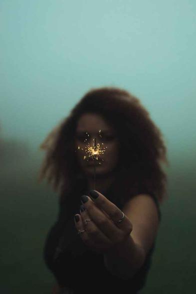 woman holding sparkler under fog